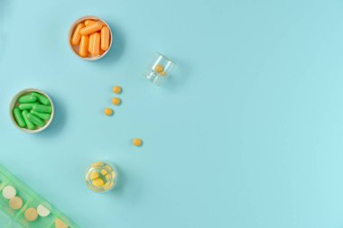 Kavanozlardaki tabletler ve mavi arka plandaki ilaç kutusu. Düz yerde, üst tarafta. Boşluğu kopyala