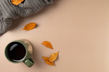 Bej arka planda yaprakları olan bir fincan çay. Düz yerde, üst tarafta. Boşluğu kopyala