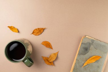 Bej arkaplanlı ve yapraklı bir fincan çay. Düz yatış, üst görünüm.