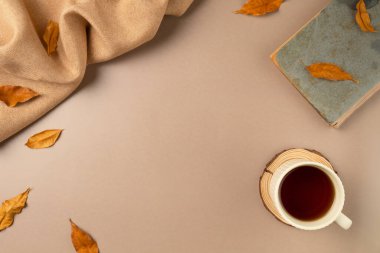 Bej arkaplanlı ve yapraklı bir fincan çay. Düz yerde, üst tarafta. Boşluğu kopyala