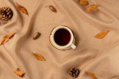 Kahverengi kumaşlı bir kupa çay ve kavram olarak yapraklar. Düz yatış, üst görünüm.