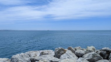 Sakin Mavi Okyanus Suları ve Rocky Shoreline Açık Mavi Gökyüzü Altında Güneşli Bir Gün.