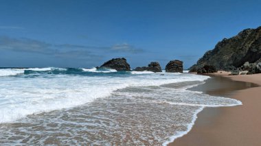 Güneşli bir günde Çöken Dalgalar ve Rocky Outcrops ile Sahilde Manzaralar. Deniz Burnu.