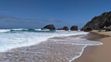 Güneşli bir günde Çöken Dalgalar ve Rocky Outcrops ile Sahilde Manzaralar. Deniz Burnu.