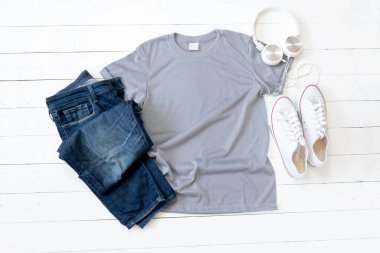Grey T Shirt mockup weathered, canvas shoes, earphones and Jeans on white wood background shirt templat