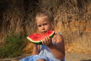 Gün batımında kumsalda oturmuş karpuz yiyen tatlı bir kız..