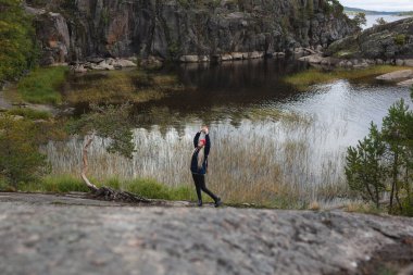 Genç ve güzel bir kız sonbahar ormanında büyük bir gölün arka planında.