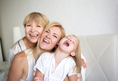 Aile portresi: Anne, kız ve torun yatak odasındaki yatakta oturuyorlar..