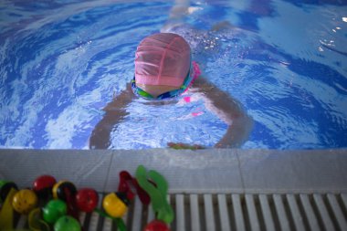 Küçük tatlı kız havuzda egzersiz yapıyor..