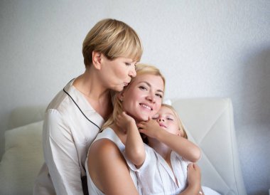 Aile portresi: Anne, kız ve torun yatak odasındaki yatakta oturuyorlar..