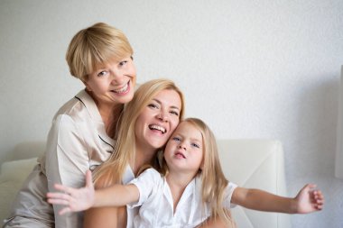 Aile portresi: Anne, kız ve torun yatak odasındaki yatakta oturuyorlar..