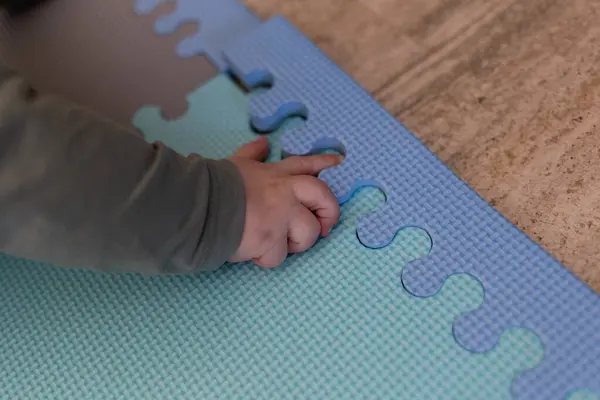 stock image A tiny hand carefully assembling foam puzzle pieces, exploring textures and colors