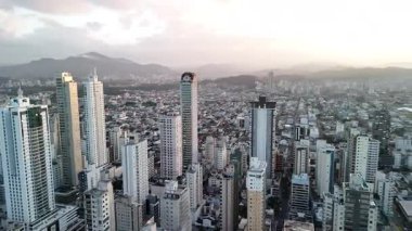 Balnear io Camboriu 'daki modern gökdelen siluetinin çarpıcı hava manzarası. Arka planda dağlar olan yüksek yoğunluklu şehir manzarasını gösterir.