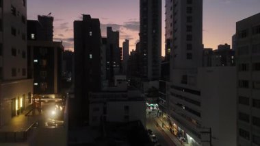 Karanlık çöktüğünde şehir sokağından yükselen bir hava aracı görüntüsü parlayan şehir manzarasını ve uzak yamaçtaki ikonik İsa heykelini gözler önüne seriyor..