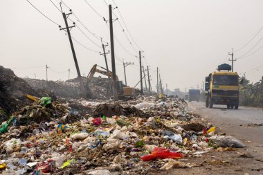 Ana yolun kenarına ev, sanayi ve tıbbi çöp yığını bırakılmış. Atıkları bu şekilde boşaltmak çevreyi kirletir. 14 Şubat 2024 'te Bangladeş' in Kishoreganj ilçesinde