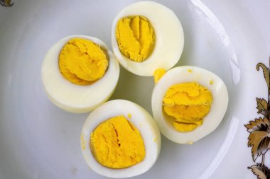 İki haşlanmış yumurta bir tabakta dört parçaya bölünür. Beslenme kavramı.