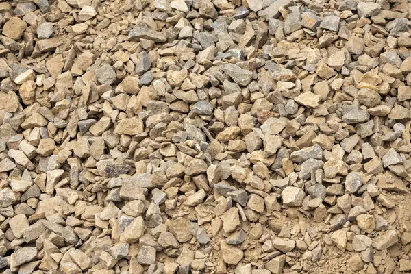 Crushed gray and light brown construction stones. Beautiful scattered granite stones background. Texture of crushed granite rocks.