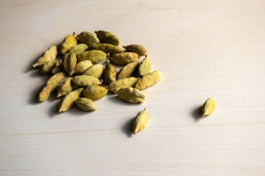 A heap of cardamom isolated on a wooden background. Its scientific name is Elettaria cardamomum and locally in Bangladesh, it is called Elachi. clipart