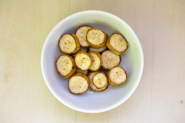 Muz, ahşap arka planda bir kasede dilimler. Sağlıklı vitamin atıştırmalığı. Üst görünüm.