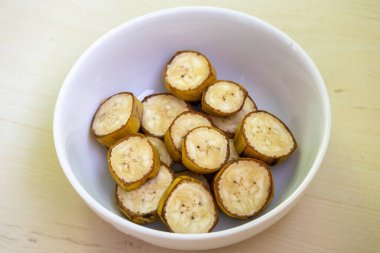 Muz, ahşap arka planda bir kasede dilimler. Muz birçok önemli besin maddeleri içerir ve sindirim, kalp sağlığı ve kilo kaybı için faydalar sağlar. Sağlıklı doğal vejetaryen yemekleri.