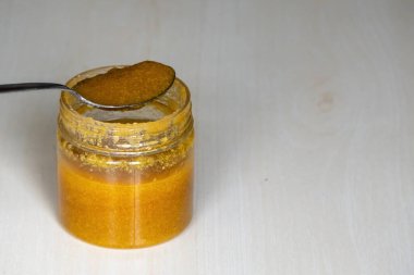 Ahşap zemin üzerinde çelik kaşık olan kavanozdaki tereyağı. Ghee zengin bir vitamin, antioksidan ve sağlıklı yağ kaynağıdır.. 