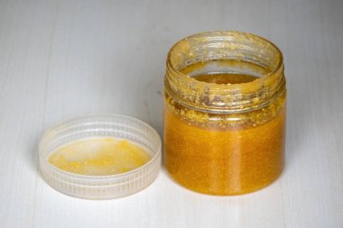 Ghee or clarified butter in a jar on a wooden background. It contains vitamins A, D, E, and K, which help with bone and vision health, and boost the immune system. clipart
