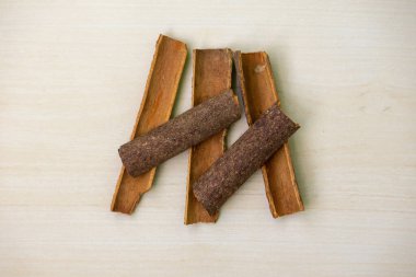 Tarçınlı çubuklar ahşap bir arka planda. Yemek pişirmek için aromalı sos. Darchini, daruchini, dalchini, tarçın kalemi, cassia kabuğu, tarçın dalı veya cassia aromaticum olarak da bilinir..