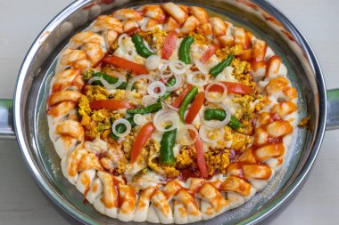 Pişmemiş ya da yapışmamış tavada çiğ pizza. Domatesli, biberli, soğanlı, yeşil biberli, soslu ve kekik tozlu sağlıklı bir yumurtalı pizza. Lezzetli ev yapımı yemek tarifi.