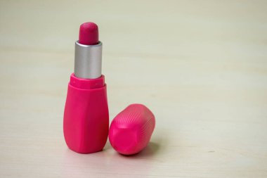 Kırmızı pembe ruj, ahşap bir arka planda izole edilmiştir. Kadınlar için kozmetik ürünleri.