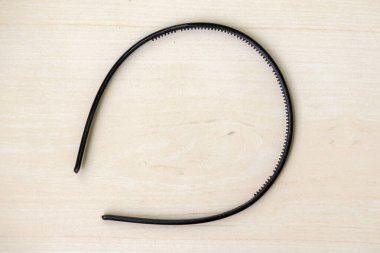 Siyah saç bandı ahşap bir arka planda izole edilmiş. Hem erkekler hem de kadınlar giyebilir..