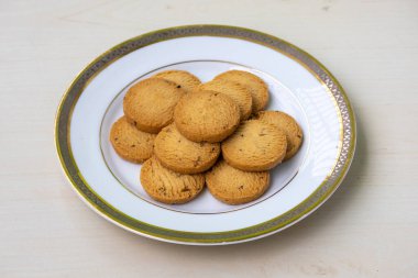 Tahta arka planda beyaz bir tabakta servis edilen lezzetli bisküviler. Bisküviler her zaman yenebilir. Kahvaltı, öğle yemeği, akşam yemeği ve tatlı da dahil..