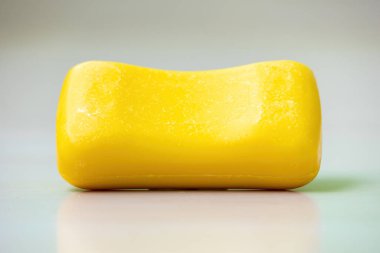 Beyaz arka planda sarı bir sabun çubuğu.