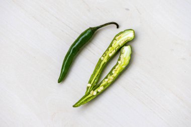 Bir yeşil biber ve ahşap yüzeyde ikiye bölünmüş bir kırmızı biber. Üst görünüm