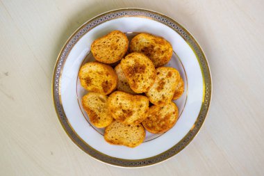 Ahşap arka planda beyaz bir tabakta baharatlı tost bisküvileri. Üst görünüm