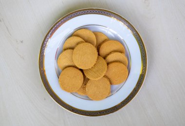 Delicious sugar-free cookies on a white plate on a wooden background. Top view of tasty biscuits.