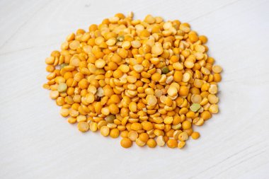 Hafif ahşap arka planda izole edilmiş kuru sarı bezelye yığını. Bezelyeler karbonhidrat, protein ve lif açısından zengindir ve birçok mineral içerirler..