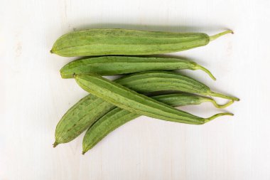 Hafif ahşap bir yüzeye yerleştirilmiş bir grup taze kabak. Çin bamyası, İpek kabağı, Jhinga ve Turai olarak da bilinir..