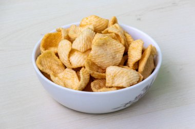 Hafif ahşap arka planda beyaz bir kasede leziz patates krakerleri..