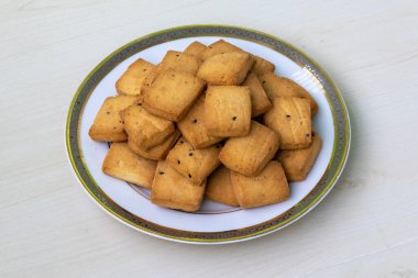 Tahta arka planda beyaz bir tabakta servis edilen lezzetli çıtır bisküviler. Lezzetli siyah kimyon bisküvileri..