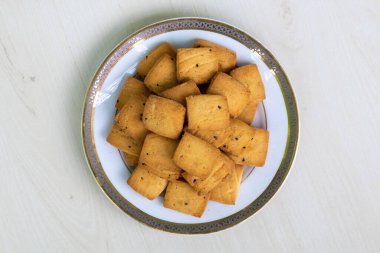 Tahta arka planda beyaz bir tabakta servis edilen lezzetli bisküviler. Üst görünüm.