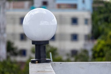 Beyaz yuvarlak cam lamba siyah çelik direkte beyaz duvarda çatı katında, arka plan bulanık.