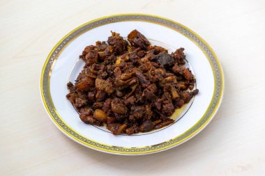 Gorur bot bhaja ya da gorur vuri bhuna beyaz bir tabakta tahta arka planda. Beef Bhuri Vaja, sığır işkembesinden yapılan popüler bir Bengali yemeğidir..
