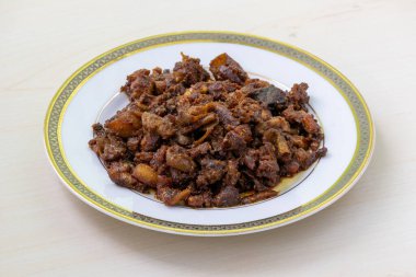 Gorur bot bhaja ya da gorur vuri bhuna beyaz bir tabakta tahta arka planda. Beef Bhuri Vaja, sığır işkembesinden yapılan popüler bir Bengali yemeğidir..