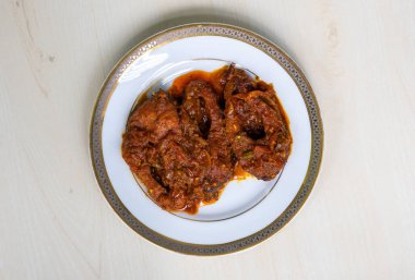 Rui balığı köri ya da rui mach bhuna beyaz bir tabakta açık ahşap yüzeyde. Geleneksel yiyecekler Bangladeş ve Hindistan 'ın Bengal bölgesinden. Üst görünüm.