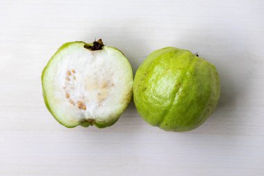 Açık ahşap bir yüzeyde sergilenen bir buçuk taze guava. Guava lezzetli ve sağlıklı bir meyvedir. Üst görünüm.