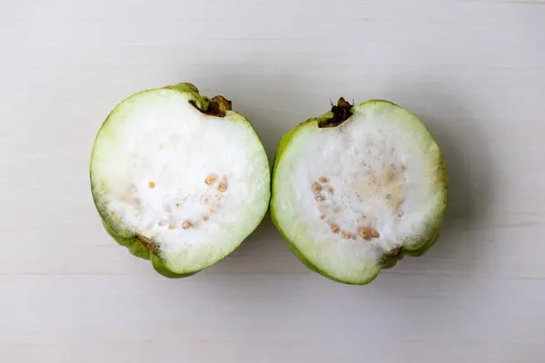 stock image Inside view of a fresh guava, sliced into two pieces. Guava is a tasty and healthy tropical fruit. Top view.