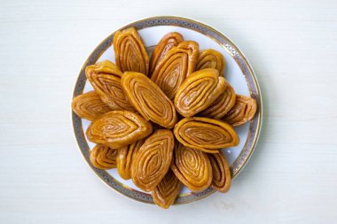 Lezzetli gaja (ayrıca khaja, chiroti veya chirote olarak da bilinir) beyaz bir tabakta açık ahşap bir yüzey üzerinde bulunur. Bu geleneksel tatlı ziyafet Bangladeş ve Hindistan 'ın Bengal bölgesinde popülerdir. Üst görünüm.