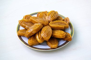 Lezzetli gaja (ayrıca khaja, chiroti veya chirote olarak da bilinir) beyaz bir tabakta açık ahşap bir yüzey üzerinde bulunur. Bu geleneksel tatlı ziyafet Bangladeş ve Hindistan 'ın Bengal bölgesinde popülerdir..