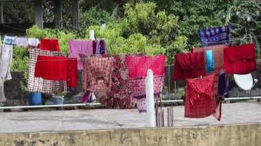 Bangladeş 'te bir evin çatısında giysiler kuruyor. Elbiseler rüzgardan dolayı sallanıyor ve kuruyor..