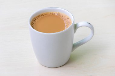 Bir fincan sıcak süt çayı ya da açık ahşap yüzeyde beyaz seramik bir fincanda dudh cha..